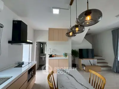 Modern open-layout kitchen and living area with stylish lighting and marble accents.