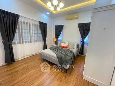 Spacious bedroom with modern decor and cozy ambiance, featuring elegant curtains and wooden flooring.