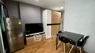 Modern living room with sleek furniture and wooden flooring, featuring a TV and dining area.