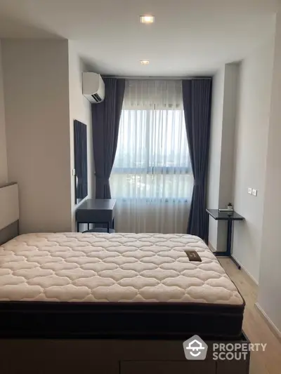 Modern bedroom with large window and minimalist decor in a stylish apartment.