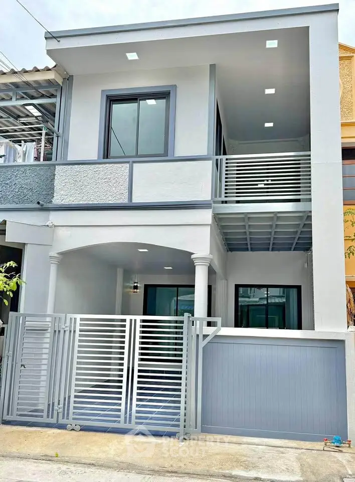 Modern two-story house with sleek design and gated entrance in urban setting.