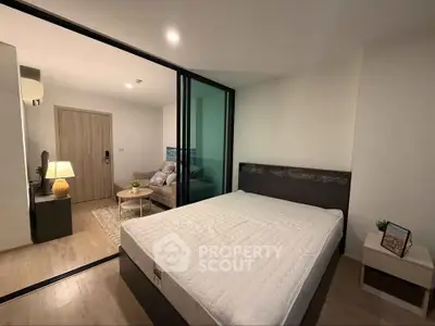 Modern bedroom with glass partition and cozy living area in stylish apartment.