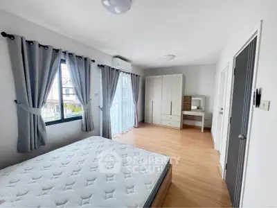 Spacious bedroom with large windows and modern furnishings in a bright, airy apartment.
