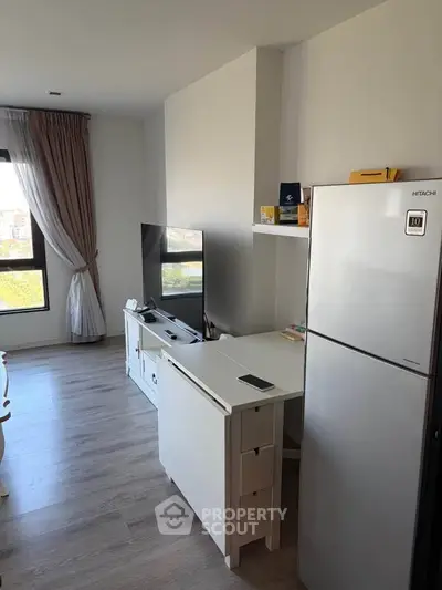 Modern living room with sleek TV setup and stylish fridge in a cozy apartment.