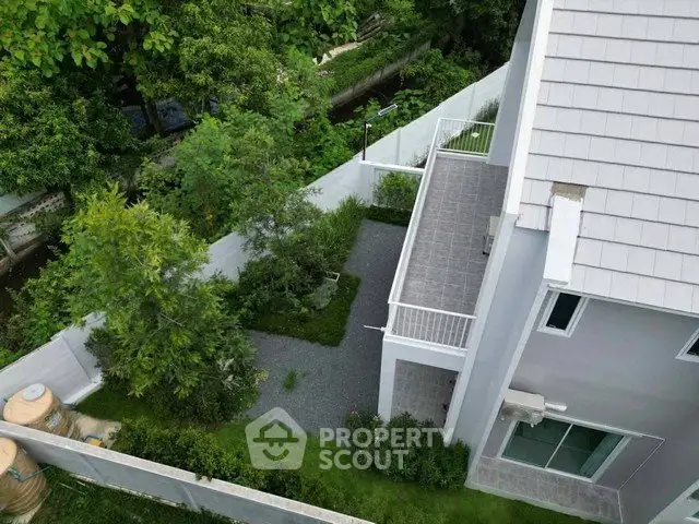 Modern two-story house with spacious garden and balcony, surrounded by lush greenery, offering serene living environment.