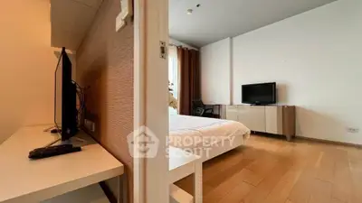 Modern bedroom with wooden flooring and dual TVs, offering a cozy and functional living space.