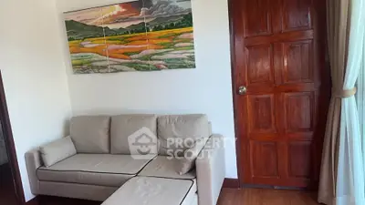 Cozy living room with beige sofa, wooden door, and landscape painting, perfect for relaxation.