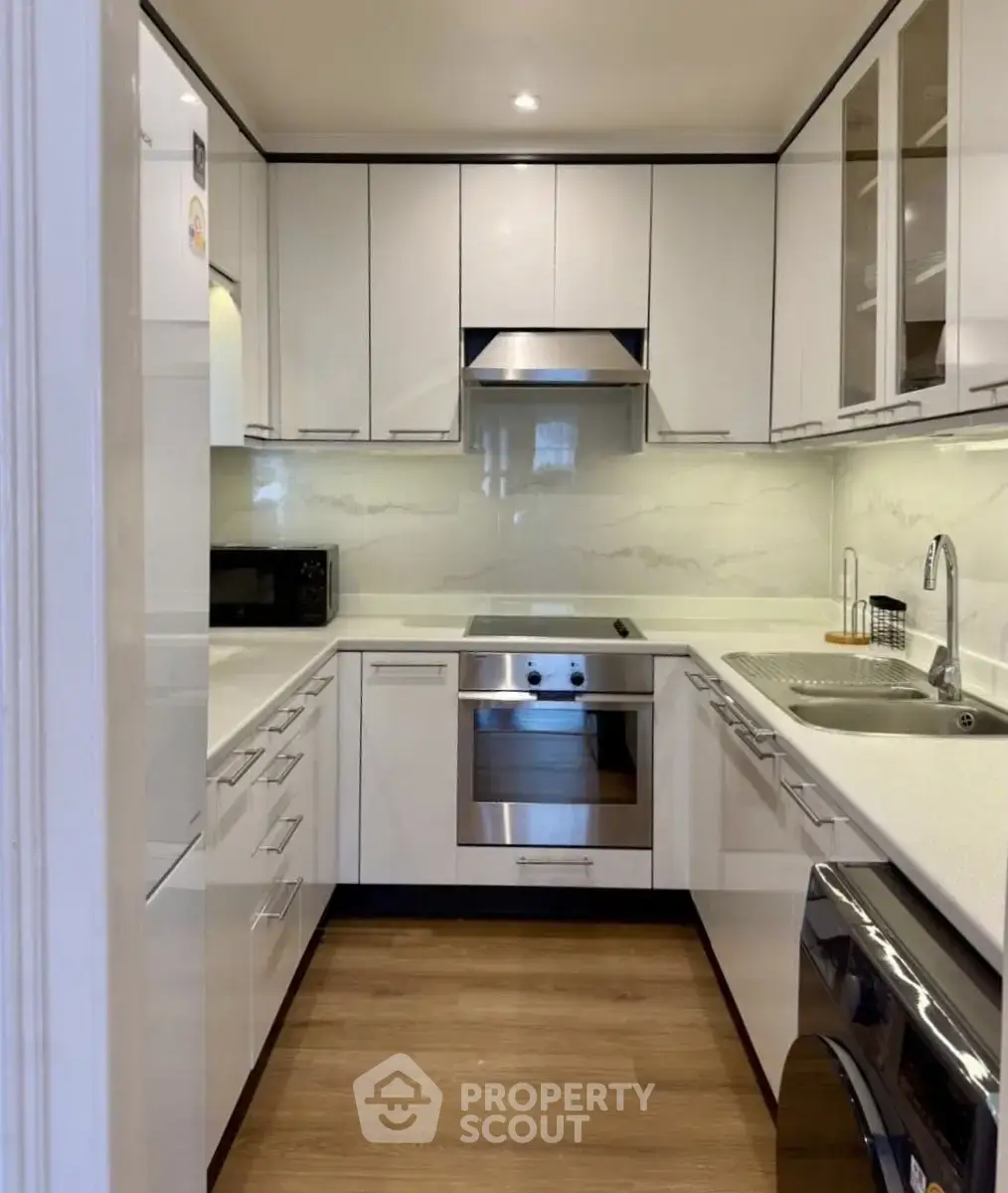 Modern kitchen with sleek white cabinetry and built-in appliances in a compact layout.
