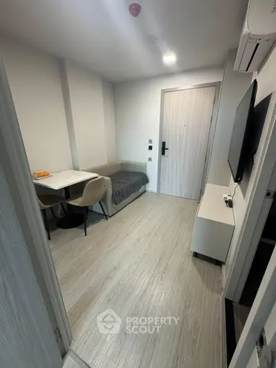 Modern compact living room with sleek furniture and wall-mounted TV in a cozy apartment.