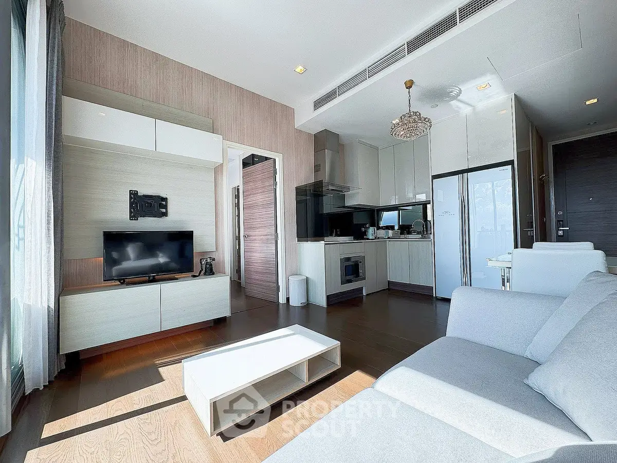 Modern living room with open kitchen, sleek furniture, and abundant natural light in a stylish apartment.