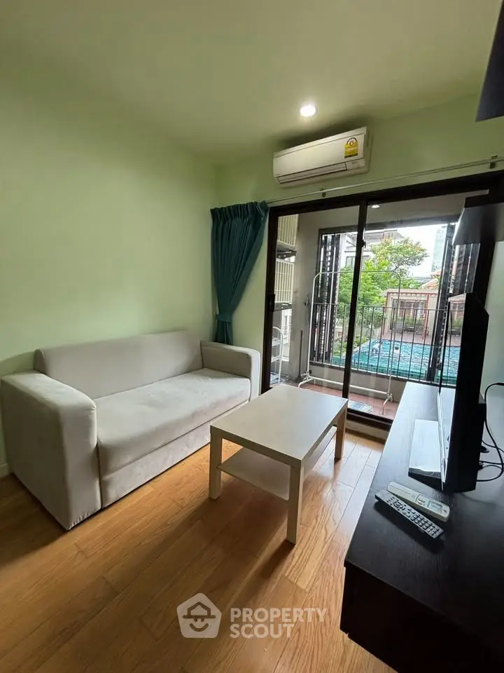 Cozy living room with balcony view, featuring a comfortable sofa and modern TV setup.