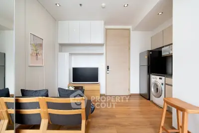 Modern living room with wooden flooring, TV, and washing machine in a stylish apartment.