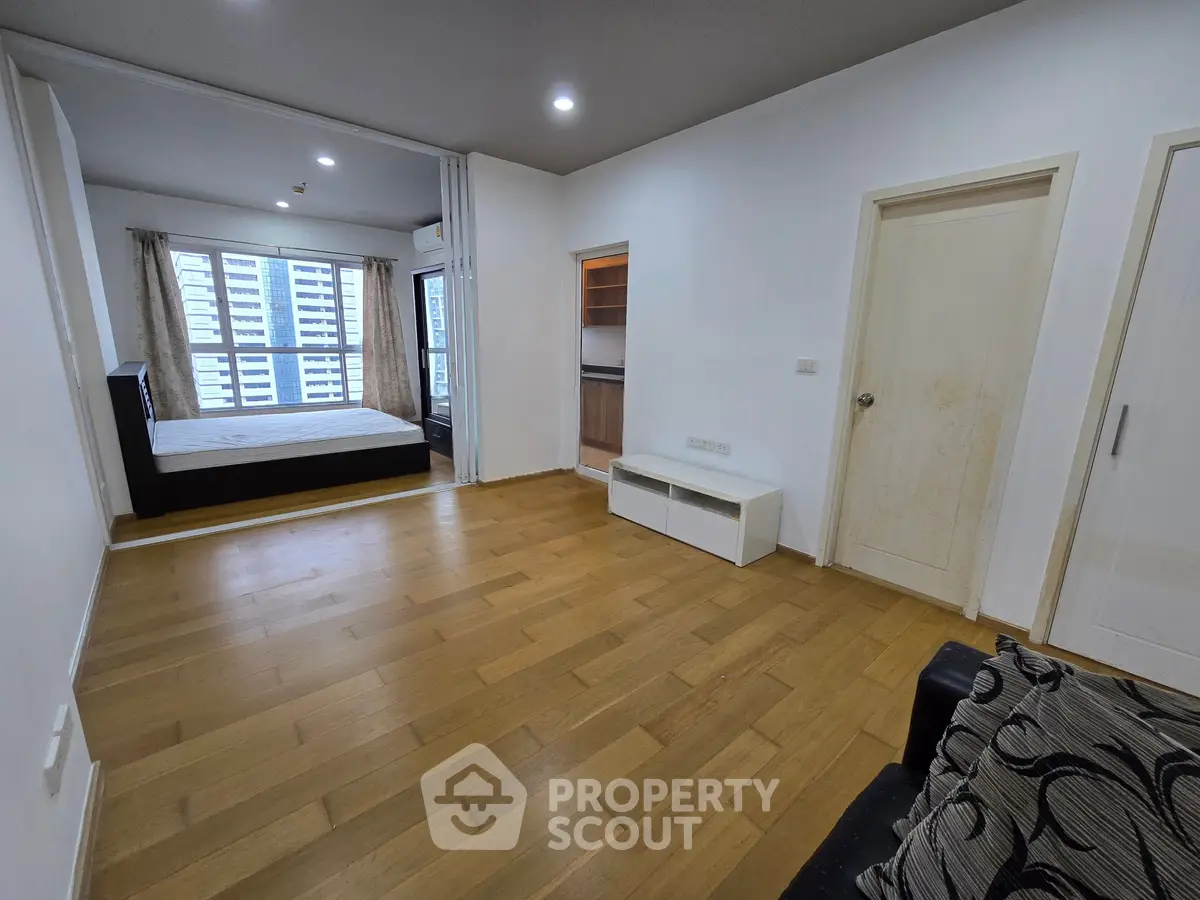 Spacious modern apartment with wooden flooring and large windows offering ample natural light.
