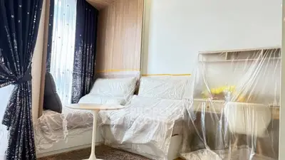 Modern living room with stylish furniture covered in protective plastic, elegant curtains, and a cozy atmosphere.