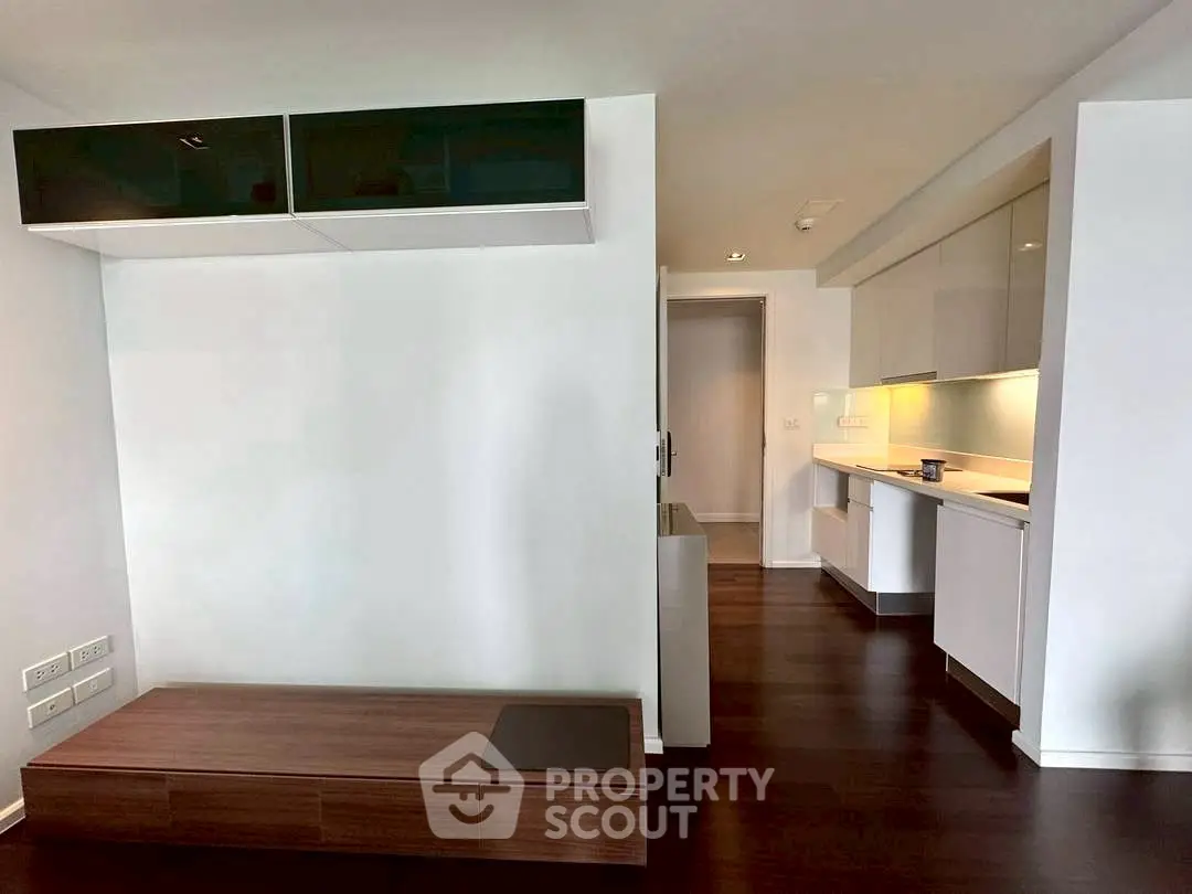 Modern minimalist kitchen with sleek cabinetry and dark wood flooring.