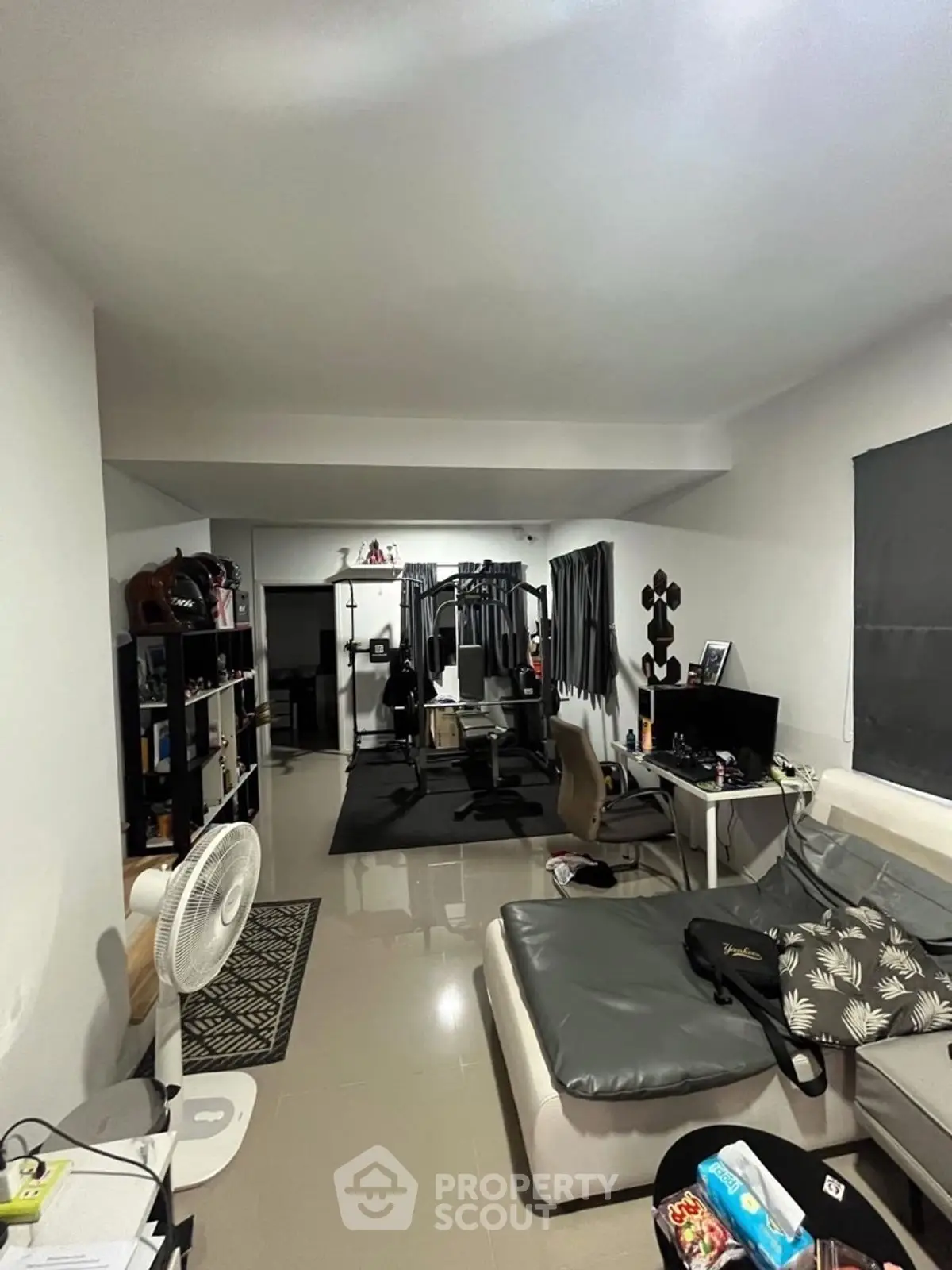 Spacious living room with modern decor and home office setup, perfect for work and relaxation.