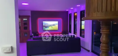 Modern living room with stylish lighting and large TV, perfect for entertainment.