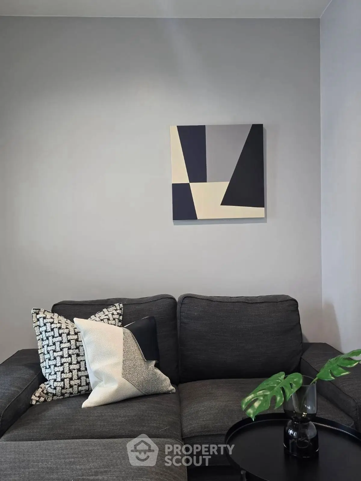 Stylish modern living room with dark sofa and abstract art on wall.