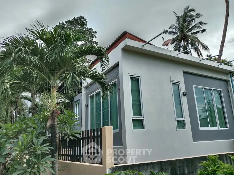 Modern tropical house exterior with lush greenery and sleek design.