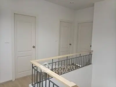 Modern interior hallway with three doors and sleek railing design