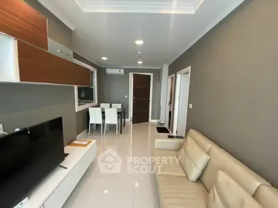 Modern living room with sleek furniture and open dining area, featuring neutral tones and contemporary design.