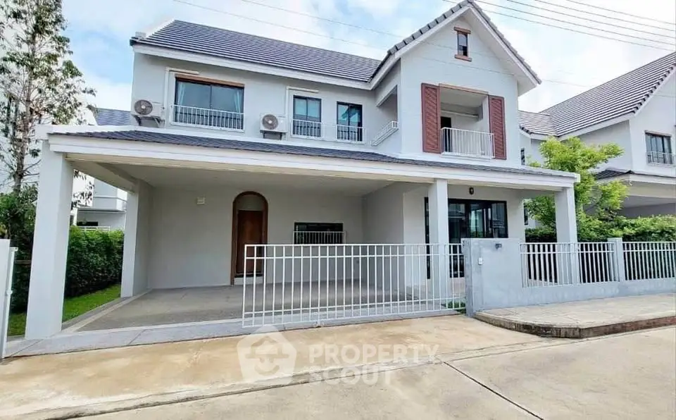 Spacious modern two-story house with a gated driveway and lush greenery.