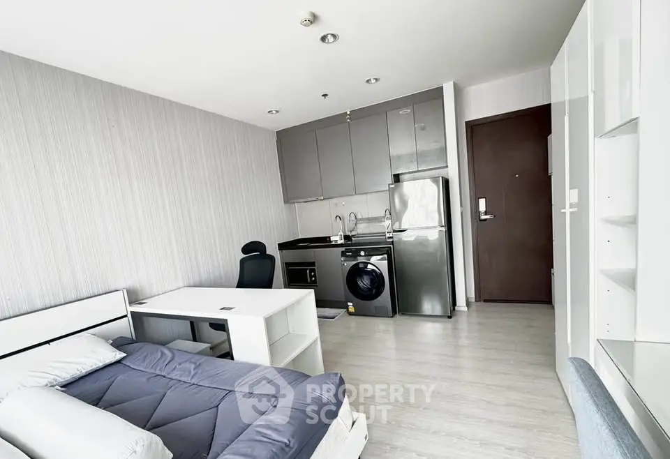 Modern studio apartment with compact kitchen and cozy sleeping area, ideal for urban living.