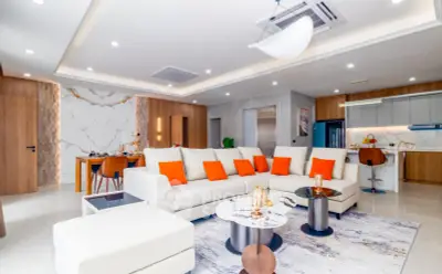 Luxurious modern living room with open kitchen, elegant decor, and vibrant accents in a spacious apartment.