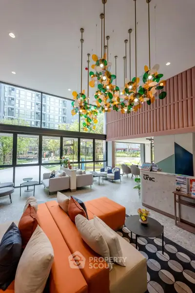 Luxurious modern lobby with vibrant chandelier and stylish seating area in upscale apartment building.