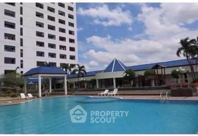 Luxurious residential building with a stunning outdoor pool and leisure area under a clear blue sky.