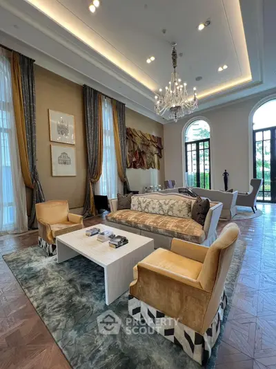 Luxurious living room with elegant chandelier and large windows, featuring plush seating and stylish decor.