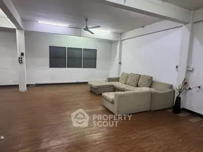 Spacious living room with sectional sofa and ceiling fan, ideal for modern living.
