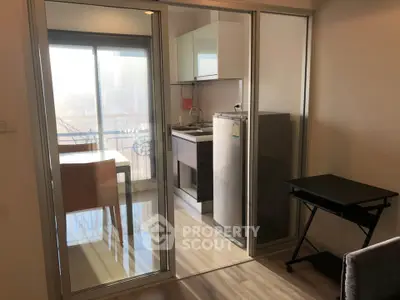 Modern apartment with glass sliding doors separating kitchen and dining area, featuring sleek appliances.