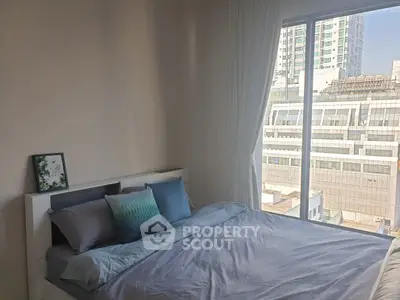 Bright bedroom with city view, modern decor, and large window for natural light.
