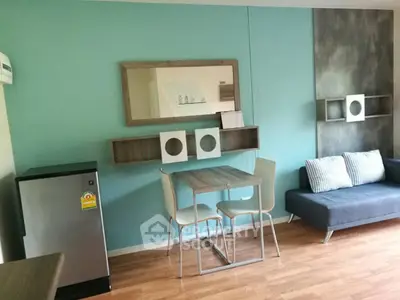Modern living room with stylish decor and compact dining area, featuring a sleek mini fridge and comfortable seating.