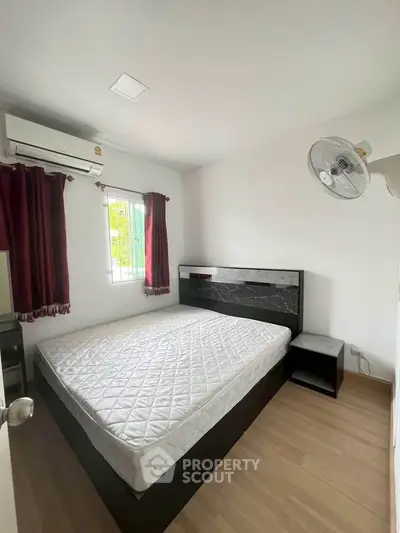 Cozy bedroom with modern bed, air conditioning, and natural light from window.