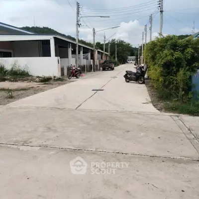 Quiet residential street with parked vehicles and greenery, ideal for peaceful living.