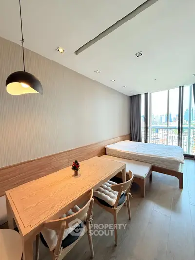 Modern studio apartment with city view, featuring a cozy dining area and comfortable bed.