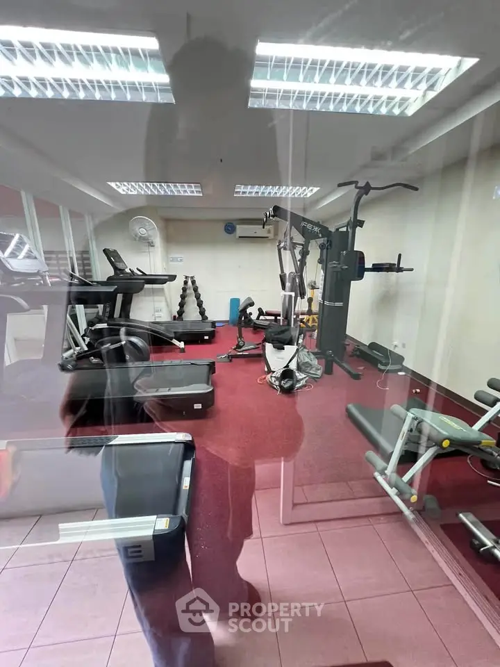 Modern gym with state-of-the-art fitness equipment and vibrant red flooring, perfect for an active lifestyle.