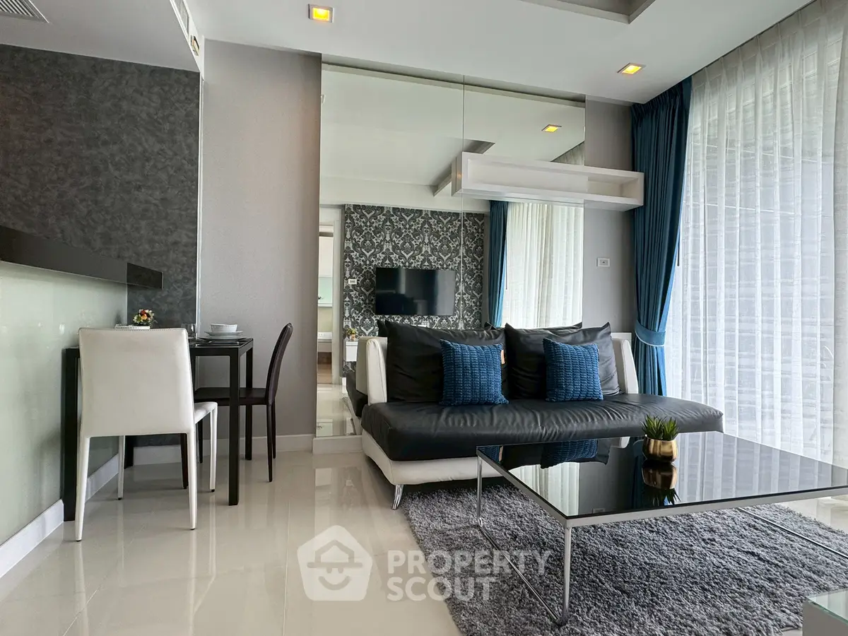 Modern living room with sleek black sofa, glass coffee table, and elegant decor.