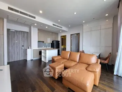 Spacious modern living room with open kitchen and stylish leather sofa.