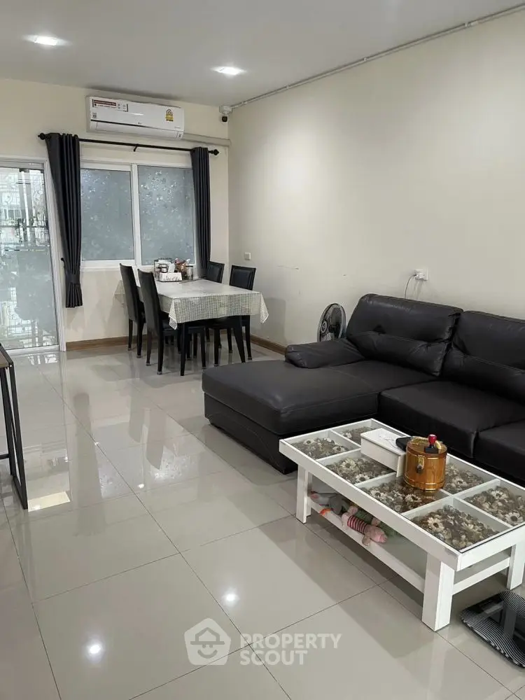 Modern living room with sleek furniture and dining area, featuring a comfortable sofa and stylish decor.