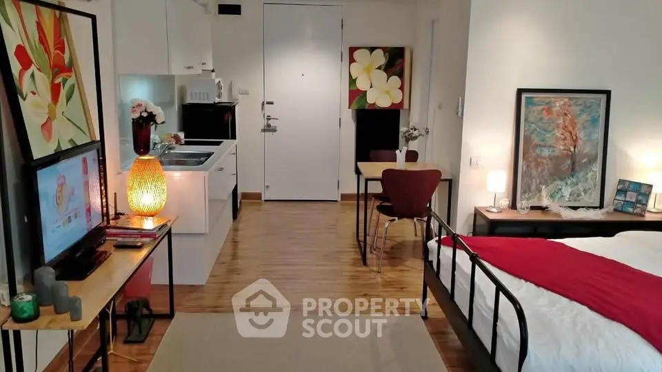 Charming studio apartment with modern decor and cozy ambiance, featuring a compact kitchen and stylish furnishings.