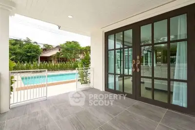 Spacious balcony with pool view and elegant glass doors in modern home.