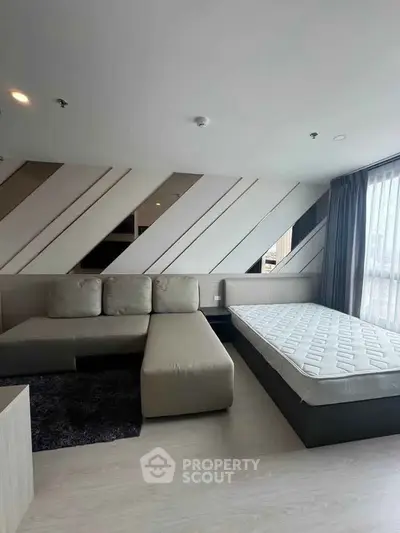 Modern living room with stylish decor and natural light, featuring a cozy sofa and bed setup.