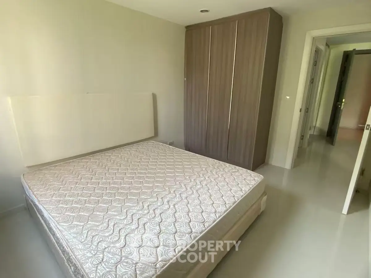 Spacious bedroom with modern wardrobe and comfortable mattress in a bright apartment.