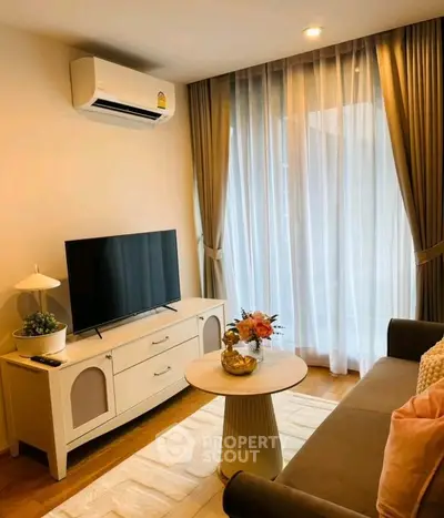 Cozy living room with modern decor, featuring a TV, air conditioning, and elegant curtains.