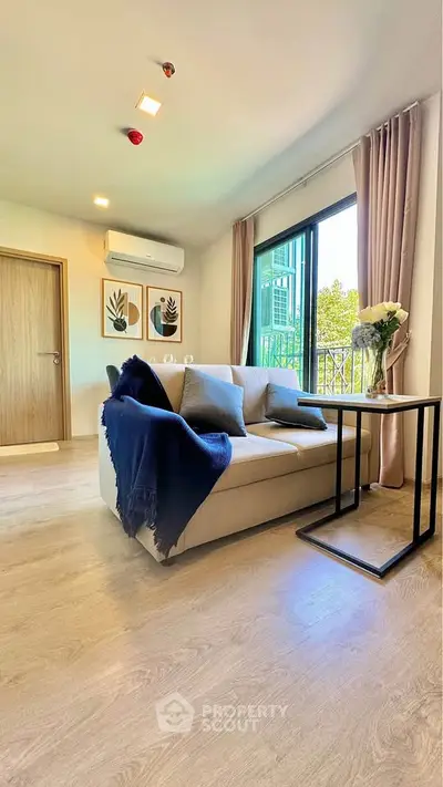 Modern living room with cozy sofa and natural light from large window.