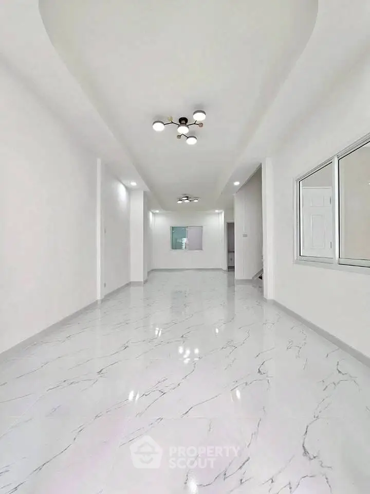 Spacious modern interior with elegant marble flooring and stylish lighting fixtures.