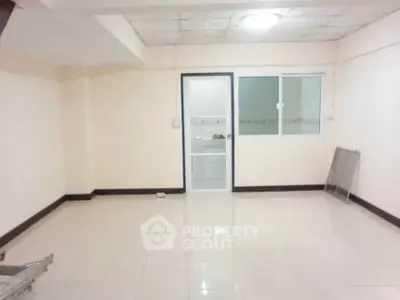 Spacious empty room with tiled floor and large window, ready for customization.